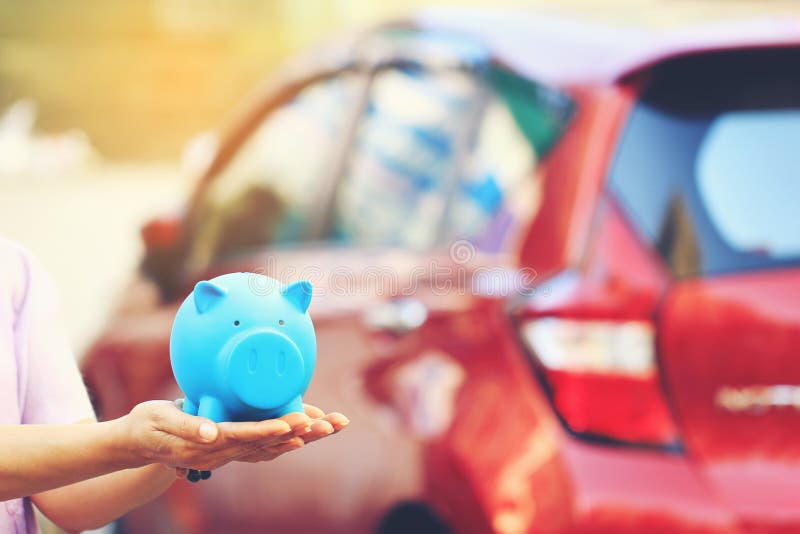 Besparingsgeld en leningen voor autoconcept, Jonge vrouw die blauw spaarvarken met status houden bij de achtergrond van het autop royalty-vrije stock foto's Besparingsgeld en leningen voor autoconcept, Jonge vrouw die blauw spaarvarken met status houden bij de achtergrond van het autop royalty-vrije stock foto's