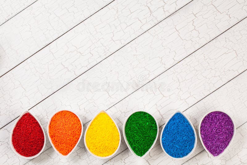A rainbow border of colorful baking sprinkles used for decorating cookies and cakes in petal shaped bowls. A rainbow border of colorful baking sprinkles used for decorating cookies and cakes in petal shaped bowls.