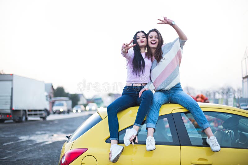 Best female friends cheering by car road trip at sunset. Happy people outdoor on vacation tour stock images Best female friends cheering by car road trip at sunset. Happy people outdoor on vacation tour stock images