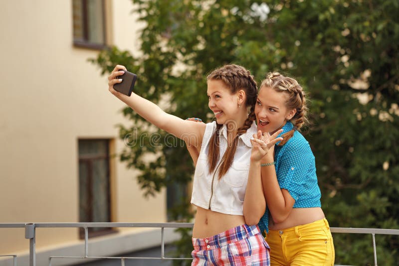 Beste Freunde, die im Park umarmen Telefon selfie stockfotos Beste Freunde, die im Park umarmen Telefon selfie stockfotos