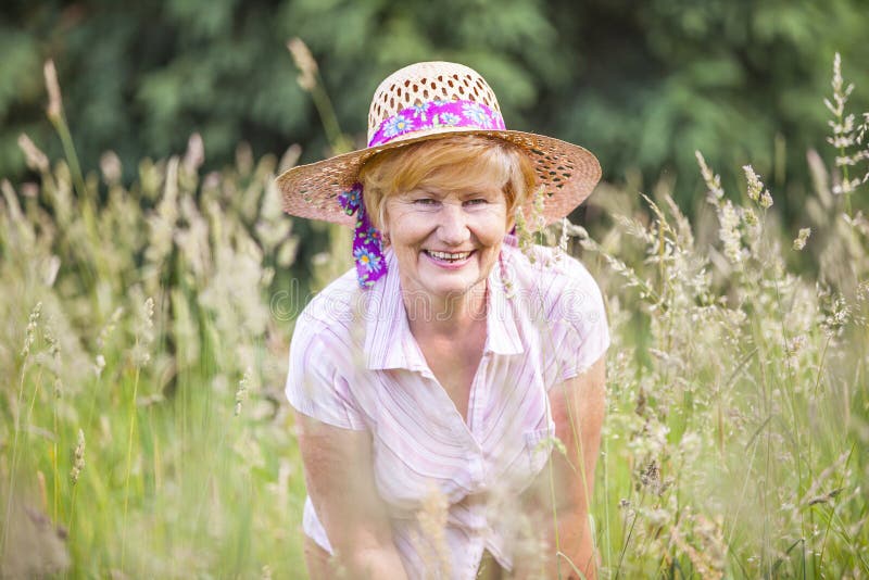 Glad Old Lady outdoors smiling among grass. Glad Old Lady outdoors smiling among grass