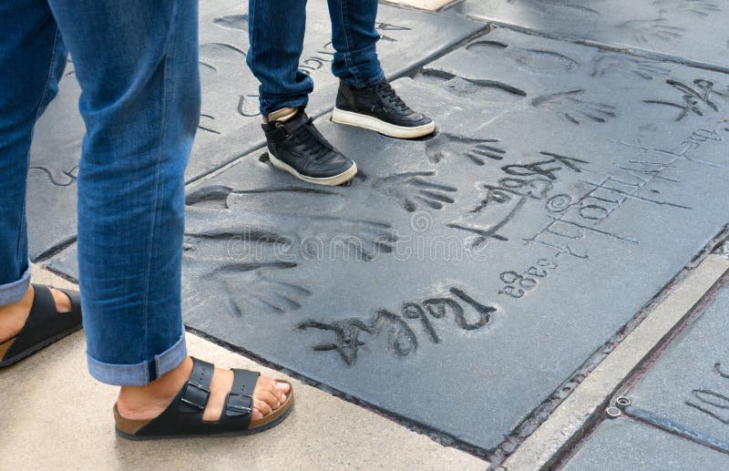 Besökareanseende för två flickor i fotspåren av Hollywood legender från filmskymningen på den Graumans kinesteatern arkivbild Besökareanseende för två flickor i fotspåren av Hollywood legender från filmskymningen på den Graumans kinesteatern arkivbild
