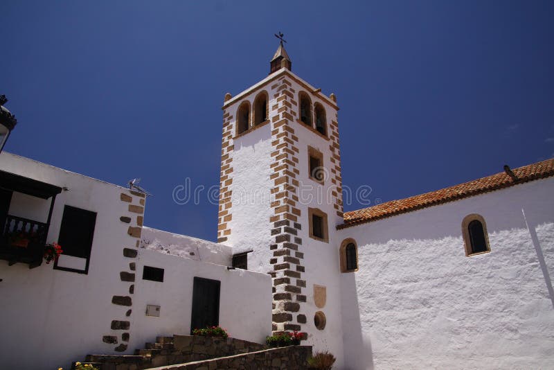 BETANCURIA, FUERTEVENTURA - JUIN 14 2019: Weergeven op witte muren en klokketoren tegen blauwe hemel stock afbeelding BETANCURIA, FUERTEVENTURA - JUIN 14 2019: Weergeven op witte muren en klokketoren tegen blauwe hemel stock afbeelding