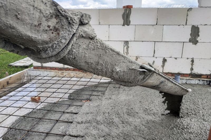 Betoniarka podaje cement przez ściek do polewania płyty betonowej, widoczne są rury kanalizacyjne