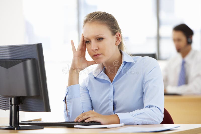 Betonte Geschäftsfrau Working At Desk im beschäftigten Büro lizenzfreies stockfoto Betonte Geschäftsfrau Working At Desk im beschäftigten Büro lizenzfreies stockfoto