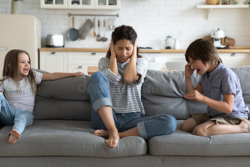Betonte junge Mutter versucht durch schlechtes Kindergeschwisterverhalten. lizenzfreie stockfotografie