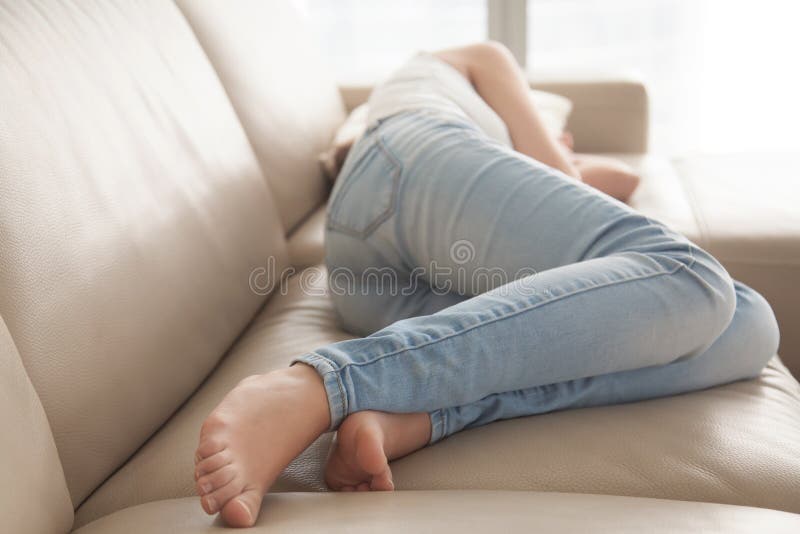 Betontes Lügenumkippen der Frau auf Sofa zu Hause stockfotos Betontes Lügenumkippen der Frau auf Sofa zu Hause stockfotos