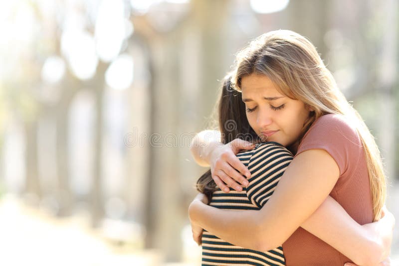 Regretful women embracing a friend reconciliating in the street. Regretful women embracing a friend reconciliating in the street