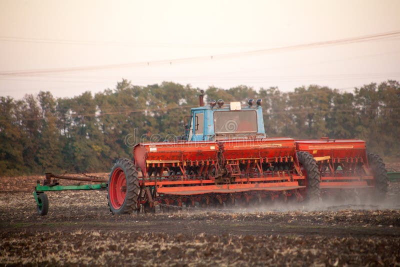 Agricultural mechanical seeders of grain crops. Tactor with a seeder sows grain in the field. A farmer on a tractor with a seeder processes the field. Agricultural mechanical seeders of grain crops. Tactor with a seeder sows grain in the field. A farmer on a tractor with a seeder processes the field.