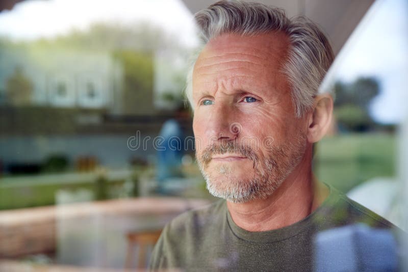 Betrokken senior man die uit de keuken-deur staat en kijkt die door het raam wordt bekeken