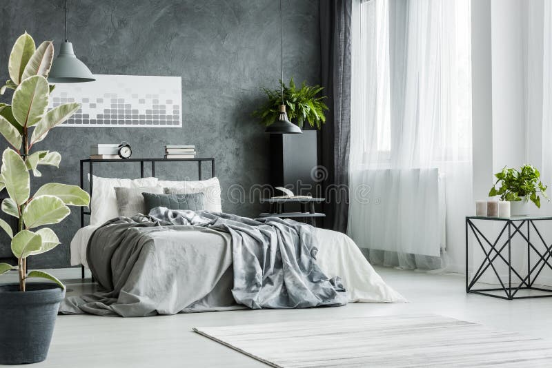 Double bed with gray sheets near the window in monochromatic bedroom interior. Double bed with gray sheets near the window in monochromatic bedroom interior