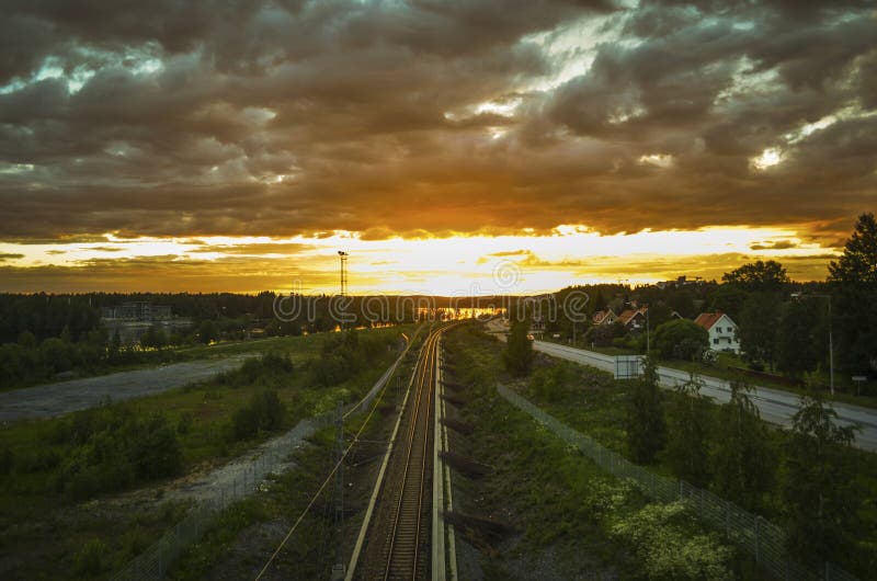 Betäubungsreflexion des Sonnenlichts auf beweglicher Wolke und der führenden Zuglinie zum orange Horizont am schönen Sommertag in lizenzfreie stockfotografie Betäubungsreflexion des Sonnenlichts auf beweglicher Wolke und der führenden Zuglinie zum orange Horizont am schönen Sommertag in lizenzfreie stockfotografie