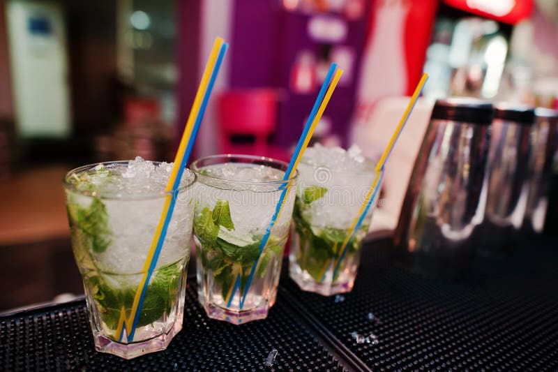 Bevanda del coctail di mojito tre con i tubi colorati alla barra immagine stock Bevanda del coctail di mojito tre con i tubi colorati alla barra immagine stock