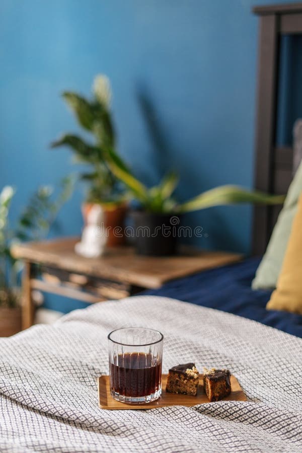Beverage and dessert on wooden tray on bed in bedroom