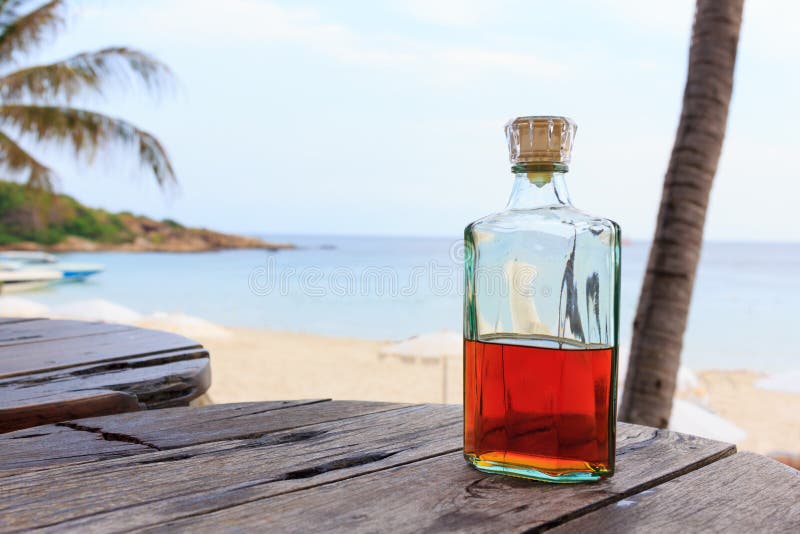 Beverrage alcohol is brandy bottle on wood table.