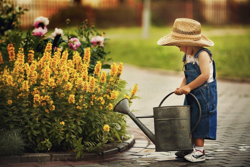 Bewässerungsblumen des kleinen Jungen stockbild Bewässerungsblumen des kleinen Jungen stockbild