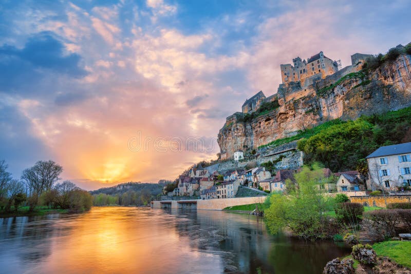 Beynac-et-Cazenac village with medieval Chateau Beynac on dramatic sunset, Dordogne, France. It is one of the most beautiful villages of France les plus beaux villages de France. Beynac-et-Cazenac village with medieval Chateau Beynac on dramatic sunset, Dordogne, France. It is one of the most beautiful villages of France les plus beaux villages de France