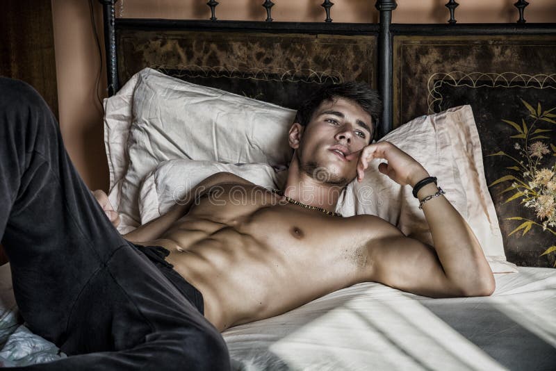 Bez koszuli seksowny samiec model kłama samotnie na jego łóżku