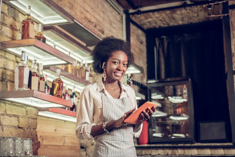 Bezaubernder afroer-amerikanisch Stangenangestellter, der Bestellschein mit Tablette ausfüllt stockfoto