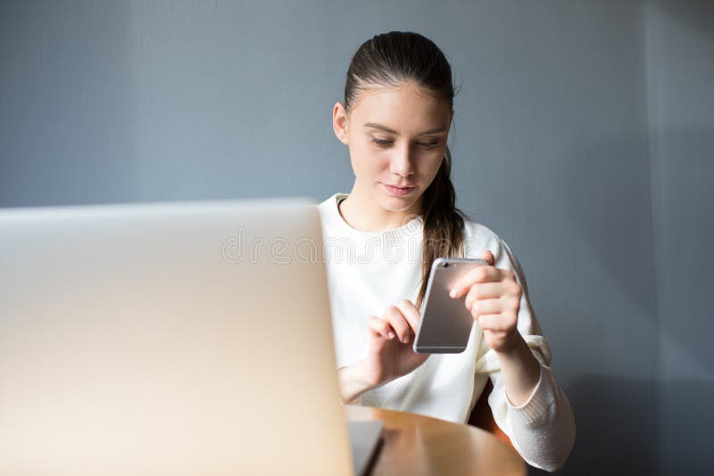 Bezaubernder Schreibentext des Hippie-Mädchens am Handy nach Telearbeit auf Laptop-Computer lizenzfreies stockfoto