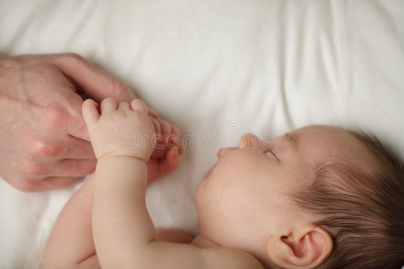 Bezauberndes Neugeborenes schlafend mit Vater Hand auf weißem Bett Hintergrund mit Kopierraum stockbild