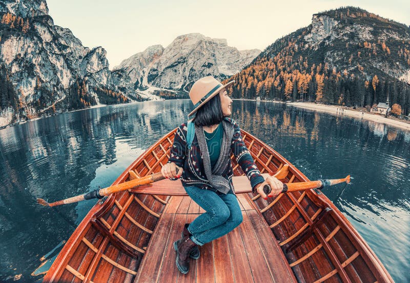 Bezbronny podróżnik z azji płynie łodzią na pięknym, górskim jeziorze jesienią