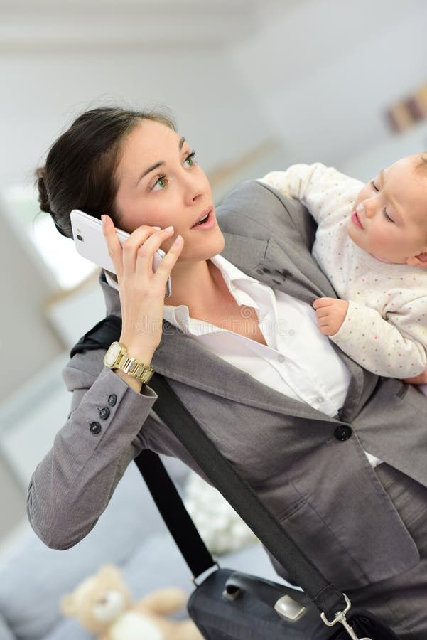 Bezige vrouw die op de telefoon spreken en haar baby vervoeren