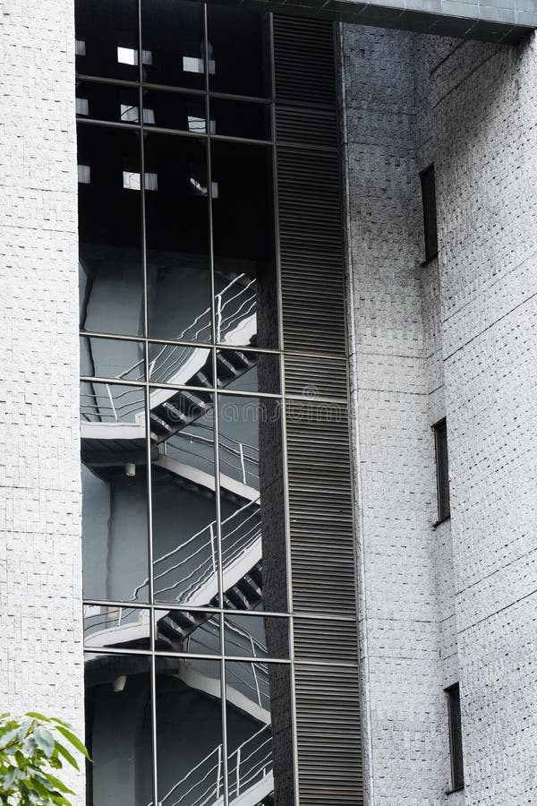 Bezinning van brandtrap in het glas van een modern gebouw met grijze cementmuren stock foto Bezinning van brandtrap in het glas van een modern gebouw met grijze cementmuren stock foto