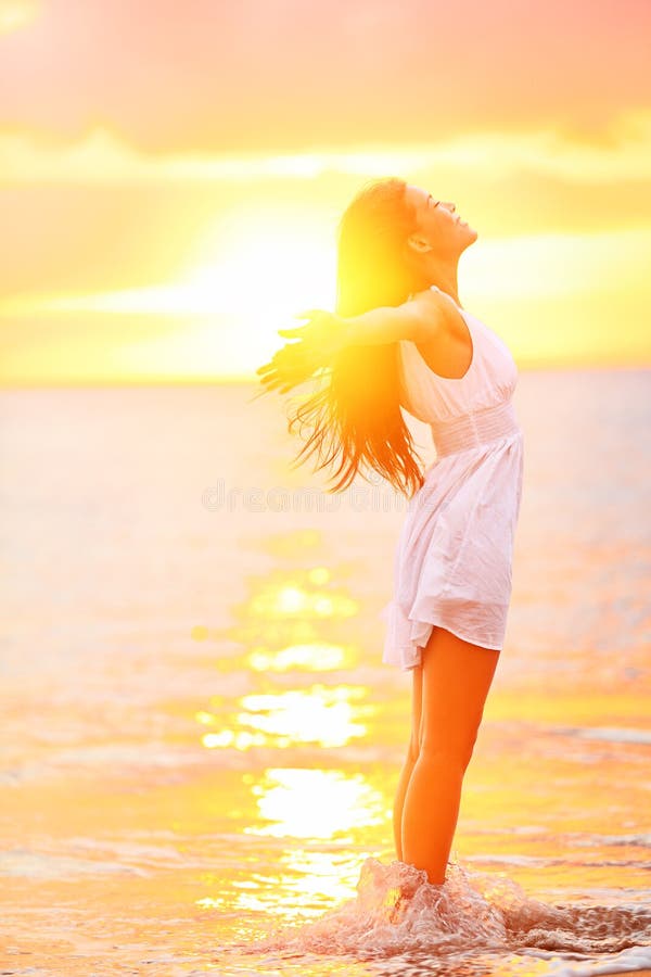 Free woman enjoying freedom feeling happy at beach at sunset. Beautiful serene relaxing woman in pure happiness and elated enjoyment with arms raised outstretched up. Asian Caucasian female model. Free woman enjoying freedom feeling happy at beach at sunset. Beautiful serene relaxing woman in pure happiness and elated enjoyment with arms raised outstretched up. Asian Caucasian female model.