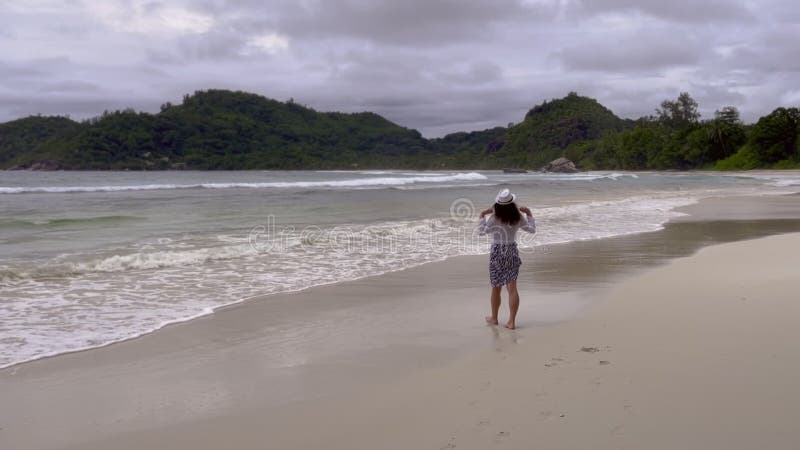 Beztroska kobieta z wyciągniętą ręką chodząca na plaży