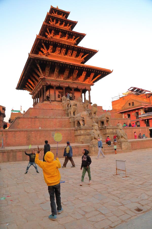 BHAKTAPUR NEPAL, GRUDZIEŃ, - 28, 2014: Dzieci bawić się Badmington przy zmierzchem przed Bhairabnath świątynią przy Taumadhi Tole zdjęcia stock BHAKTAPUR NEPAL, GRUDZIEŃ, - 28, 2014: Dzieci bawić się Badmington przy zmierzchem przed Bhairabnath świątynią przy Taumadhi Tole zdjęcia stock