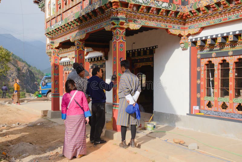 An artists who paints flowers and traditional patterns on the pillars of a house in Bhutan and is admired and observed by other people. An artists who paints flowers and traditional patterns on the pillars of a house in Bhutan and is admired and observed by other people