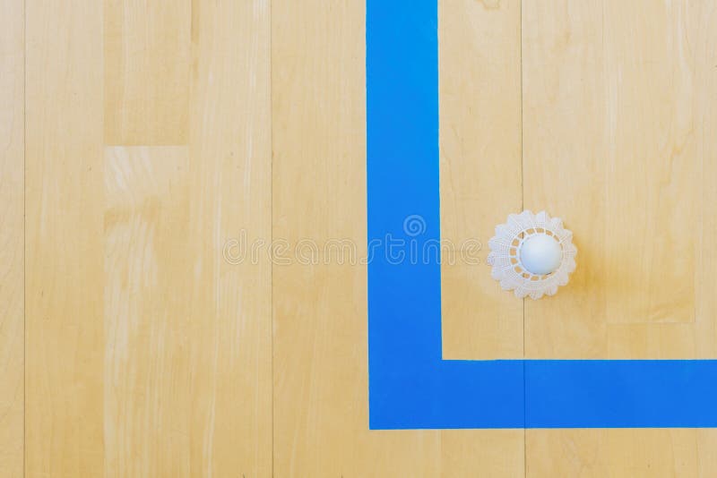 White badminton shuttlecock and blue line hall floor at badminton courts. White badminton shuttlecock and blue line hall floor at badminton courts.