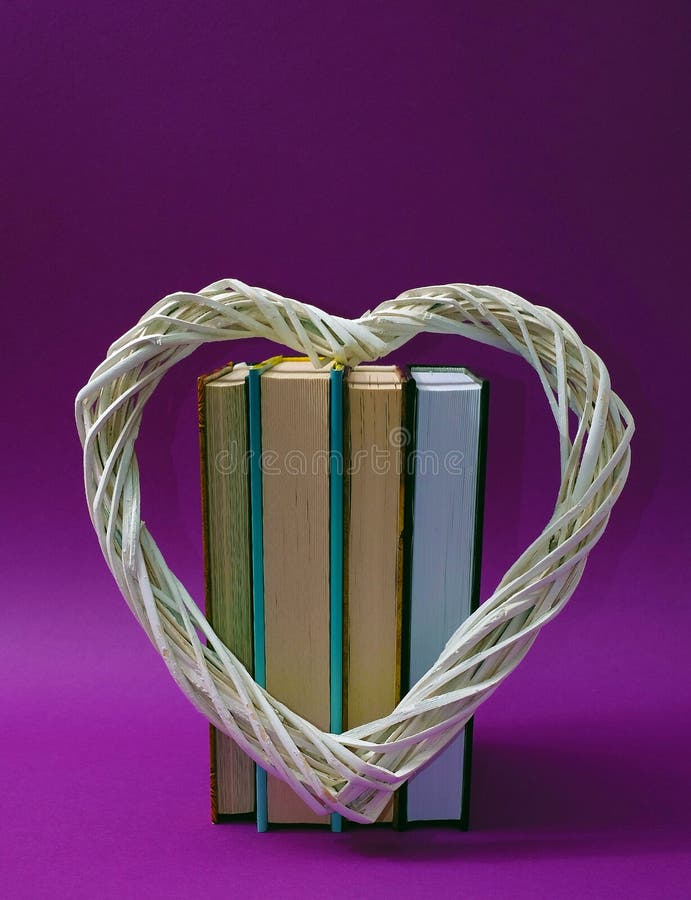 Big white heart, books in an upright position on a violet background. Text space. Valentine`s Day, book lovers, reading is in, concept. Minimal style. Big white heart, books in an upright position on a violet background. Text space. Valentine`s Day, book lovers, reading is in, concept. Minimal style