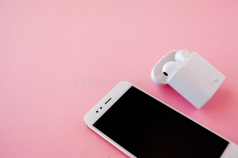 Biały bezprzewodowy smartphone i hełmofony kłamają na jaskrawym różowym tle Hełmofony w ładuje skrzynce obraz stock Biały bezprzewodowy smartphone i hełmofony kłamają na jaskrawym różowym tle Hełmofony w ładuje skrzynce obraz stock
