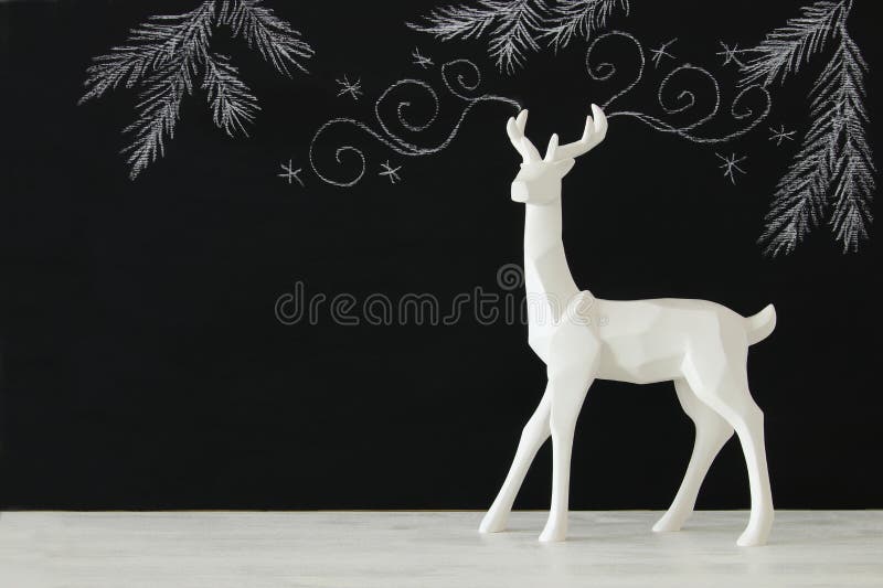 Biały renifer na drewnianym stole nad chalkboard tła whith ręki rysować kredowymi ilustracjami obraz stock Biały renifer na drewnianym stole nad chalkboard tła whith ręki rysować kredowymi ilustracjami obraz stock