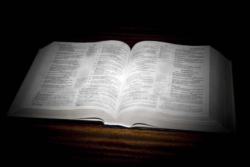 One open bible on table in black background