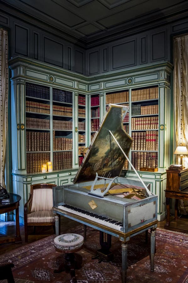 Biblioteka z półkami na książki i starożytnym fortepianem w zamku Cheverny, Dolina Loire, Francja obraz stock Biblioteka z półkami na książki i starożytnym fortepianem w zamku Cheverny, Dolina Loire, Francja obraz stock