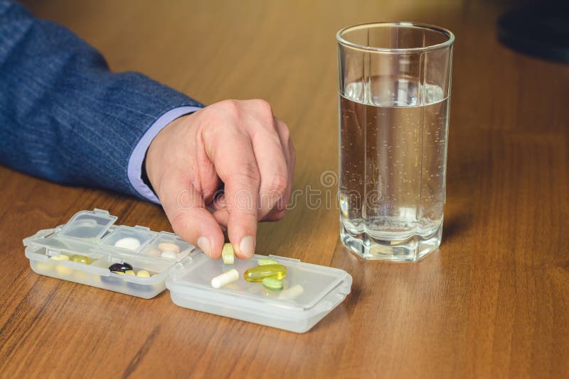 Bicchiere d'acqua, vitamine e nutrizionale, pillole dell'integratore alimentare che tengono a disposizione dell'uomo di affari su fotografie stock Bicchiere d'acqua, vitamine e nutrizionale, pillole dell'integratore alimentare che tengono a disposizione dell'uomo di affari su fotografie stock