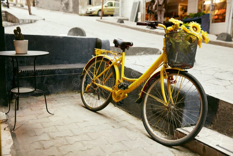 Bicicleta amarela com a cesta dos girassóis na rua da cidade imagens de stock royalty free Bicicleta amarela com a cesta dos girassóis na rua da cidade imagens de stock royalty free
