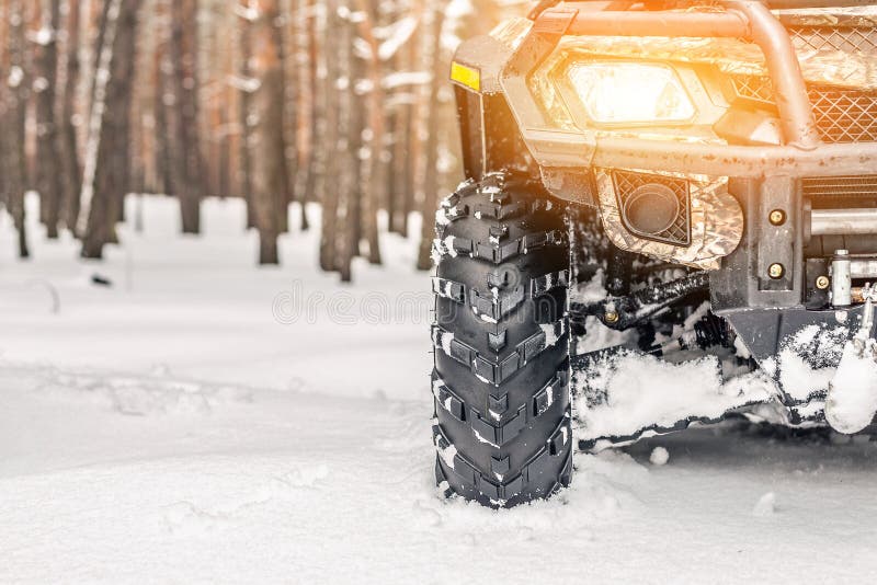 Bicicleta do quadrilátero do close-up ATV 4wd na floresta no inverno 4wd todo-terreain suporte do veículo nas nevadas fortes com imagem de stock royalty free Bicicleta do quadrilátero do close-up ATV 4wd na floresta no inverno 4wd todo-terreain suporte do veículo nas nevadas fortes com imagem de stock royalty free