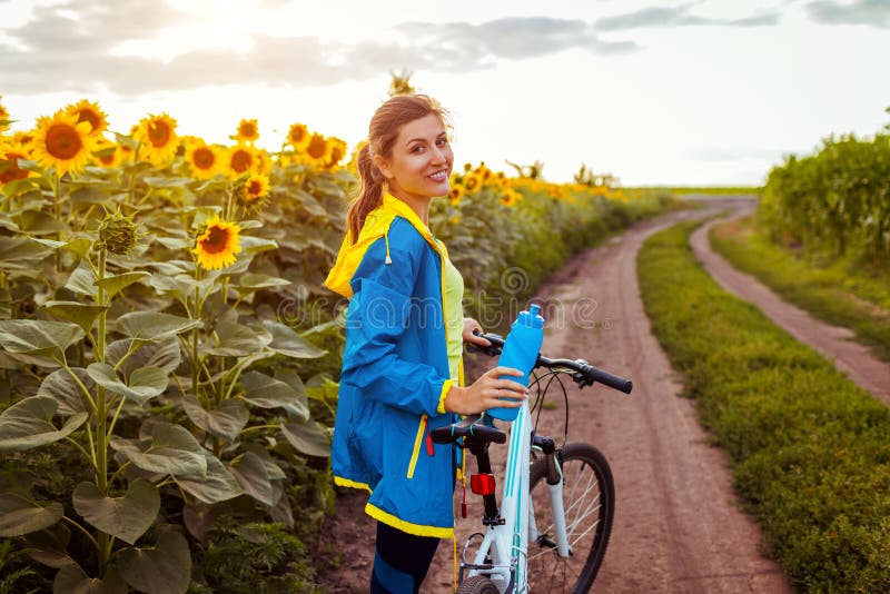 Bicicleta feliz joven del montar a caballo del ciclista de la mujer en campo del girasol Actividad del deporte del verano Forma d imagen de archivo Bicicleta feliz joven del montar a caballo del ciclista de la mujer en campo del girasol Actividad del deporte del verano Forma d imagen de archivo