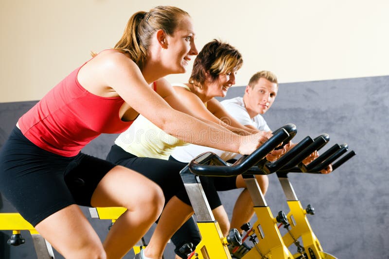 Three people spinning on bicycles in a gym or fitness club for a workout. Three people spinning on bicycles in a gym or fitness club for a workout