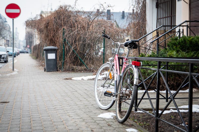 Bicicleta rosa estacionada na calçada com sinal de proibição de entrada e lixeira por perto imagens de stock