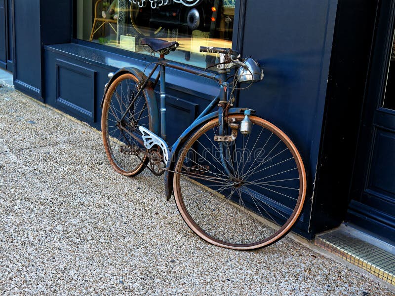 Bicicletta d'annata che pende contro una finestra del negozio fotografia stock Bicicletta d'annata che pende contro una finestra del negozio fotografia stock