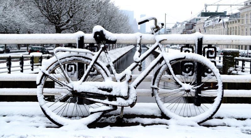 Bicicletta parcheggiata un giorno di inverno nella città immagine stock libera da diritti Bicicletta parcheggiata un giorno di inverno nella città immagine stock libera da diritti
