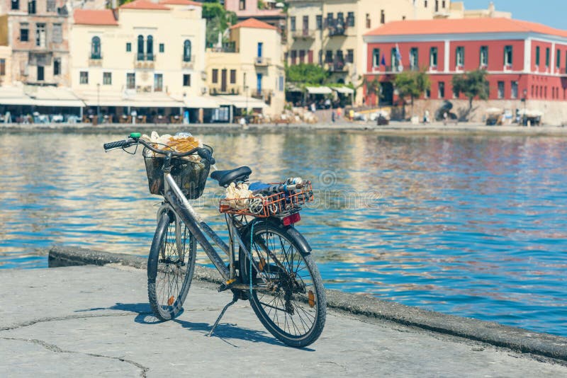 Bicicletta sulla banchina di vecchio porto veneziano sui precedenti della città di Chania Isola di Crete fotografia stock libera da diritti Bicicletta sulla banchina di vecchio porto veneziano sui precedenti della città di Chania Isola di Crete fotografia stock libera da diritti