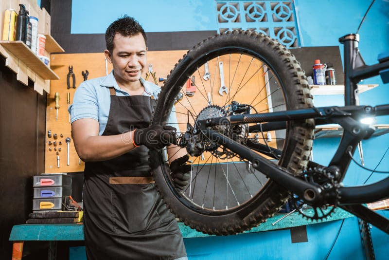 Bicycle Mechanic in Aprons Tightens Spokes while Fixing Problems Stock