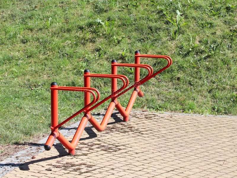 Bicycle park. Metal orange handrails for parking bicycles. A device to make life easier for cyclists. Facilities for the city`s ec stock photo Bicycle park. Metal orange handrails for parking bicycles. A device to make life easier for cyclists. Facilities for the city`s ec stock photo