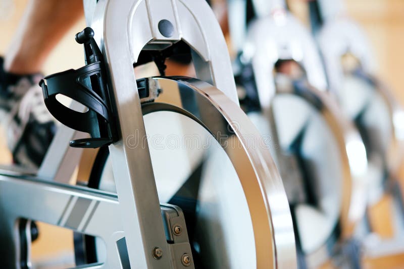 Three people spinning in the gym, exercising for their legs and cardio training, only limbs and wheels to be seen. Three people spinning in the gym, exercising for their legs and cardio training, only limbs and wheels to be seen